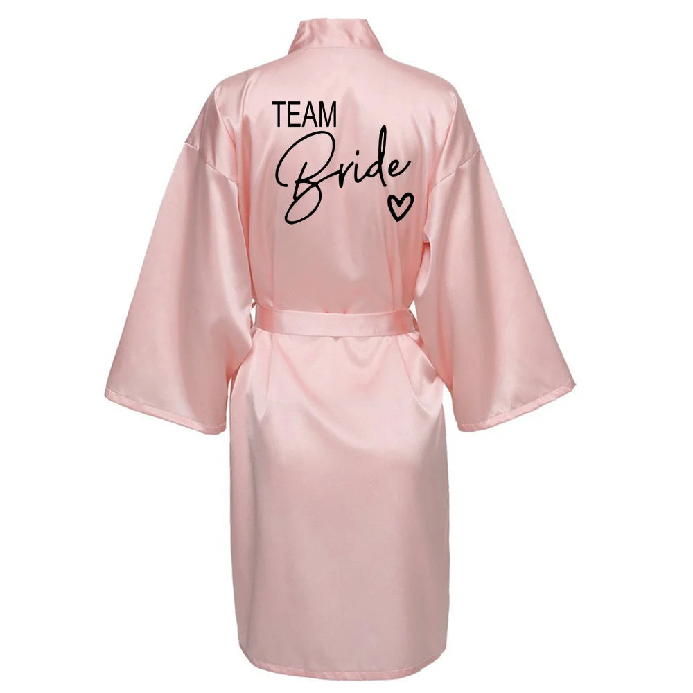 La robe kimono satinée “Wedding Party Team Bride Robe With Black Letters SP003” est un peignoir élégant pour mariée ou demoiselles d’honneur, avec inscription noire “Team Bride” au dos, idéal pour les enterreme