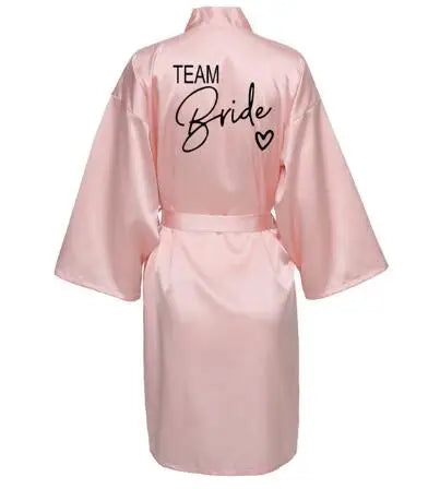 La robe kimono satinée “Wedding Party Team Bride Robe With Black Letters SP003” est un peignoir élégant pour mariée ou demoiselles d’honneur, avec inscription noire “Team Bride” au dos, idéal pour les enterreme
