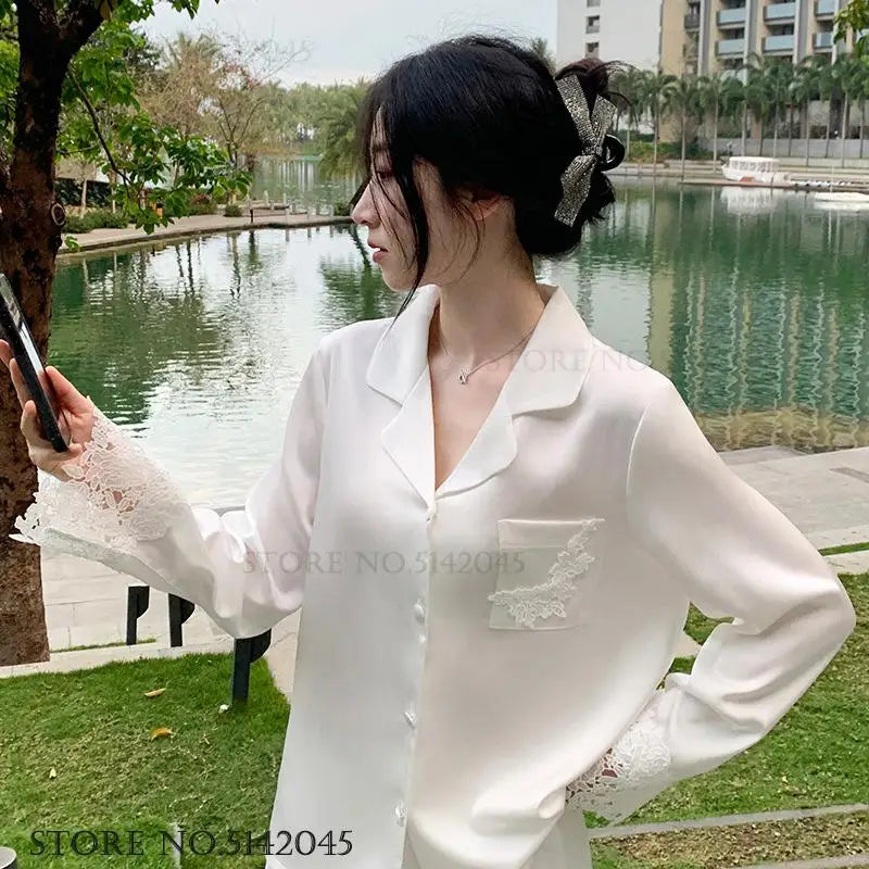 L’ensemble de pyjama de luxe pour femmes est une tenue de nuit élégante en satin soyeux blanc, ornée de dentelle, avec pantalon et haut amples pour un style casual et détendu à la maison.