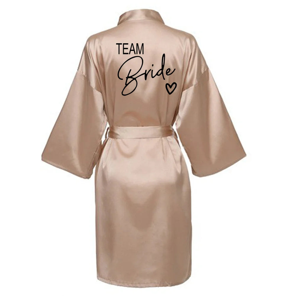 La robe kimono satinée “Wedding Party Team Bride Robe With Black Letters SP003” est un peignoir élégant pour mariée ou demoiselles d’honneur, avec inscription noire “Team Bride” au dos, idéal pour les enterreme